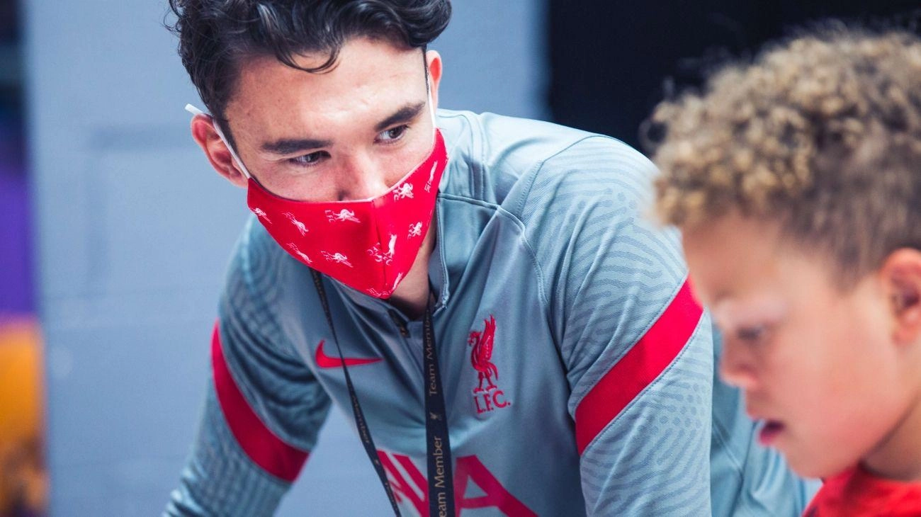 Image of young man wearing an LFC facemask talking to younger boy