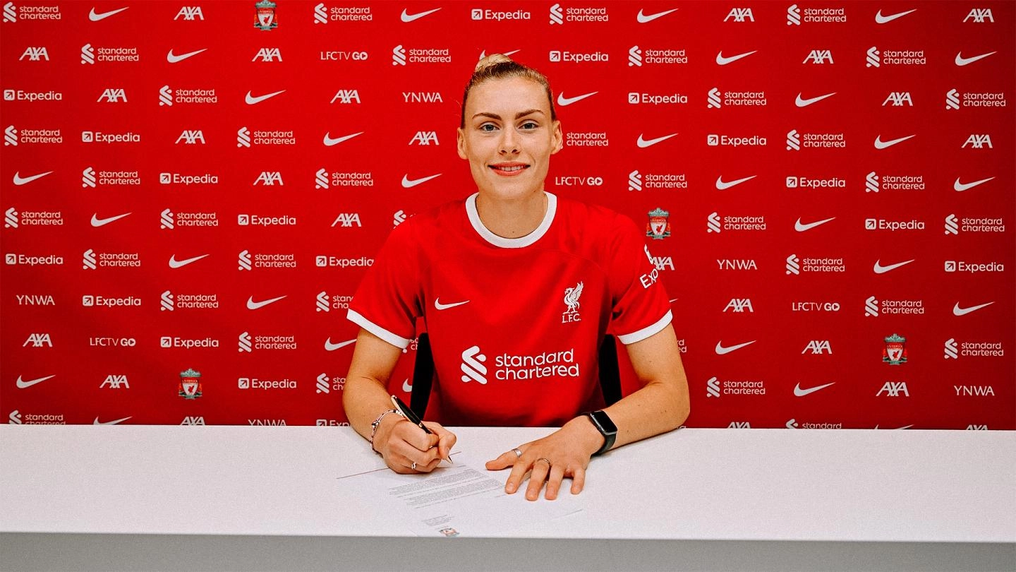 Jenna Clark smiles to the camera as she signs her Liverpool FC contract