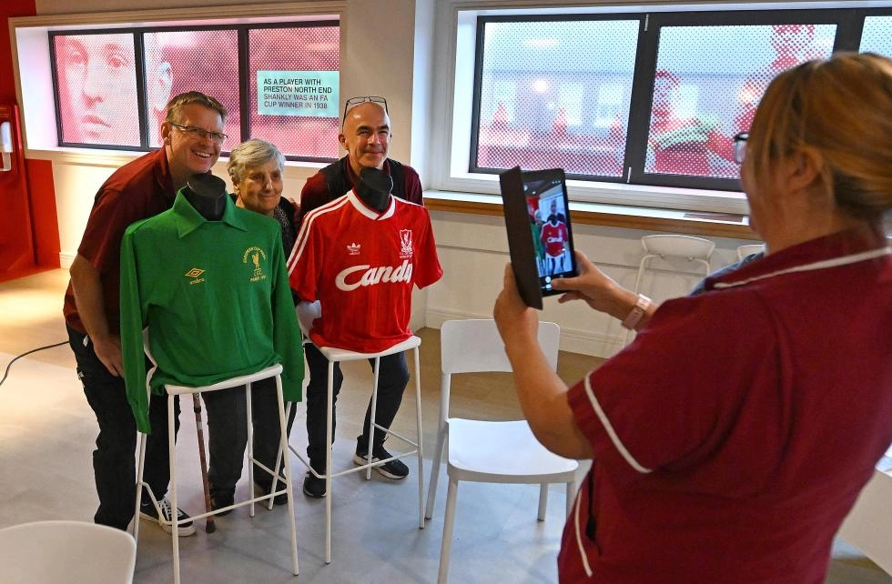 People posing with old football shirt